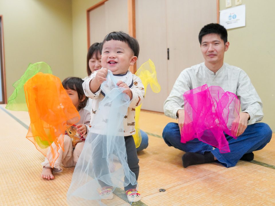 スカーフを持って笑いながら動く男の子