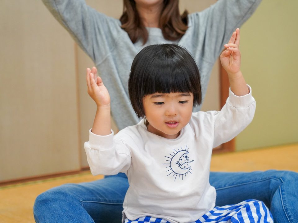 ママと一緒に両手を上げて歌う子