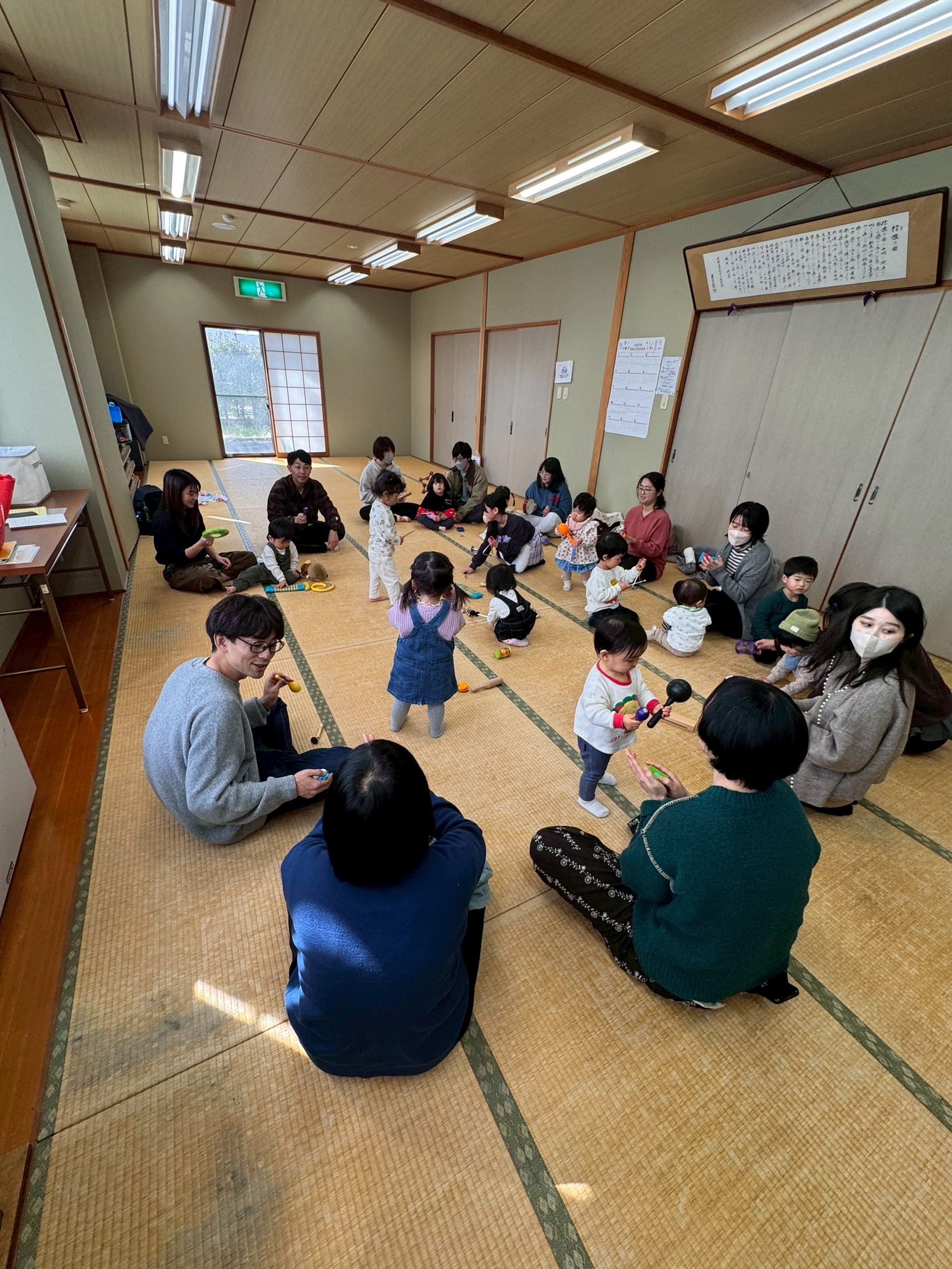 輪の外側から子どもたちを見守る大人たち