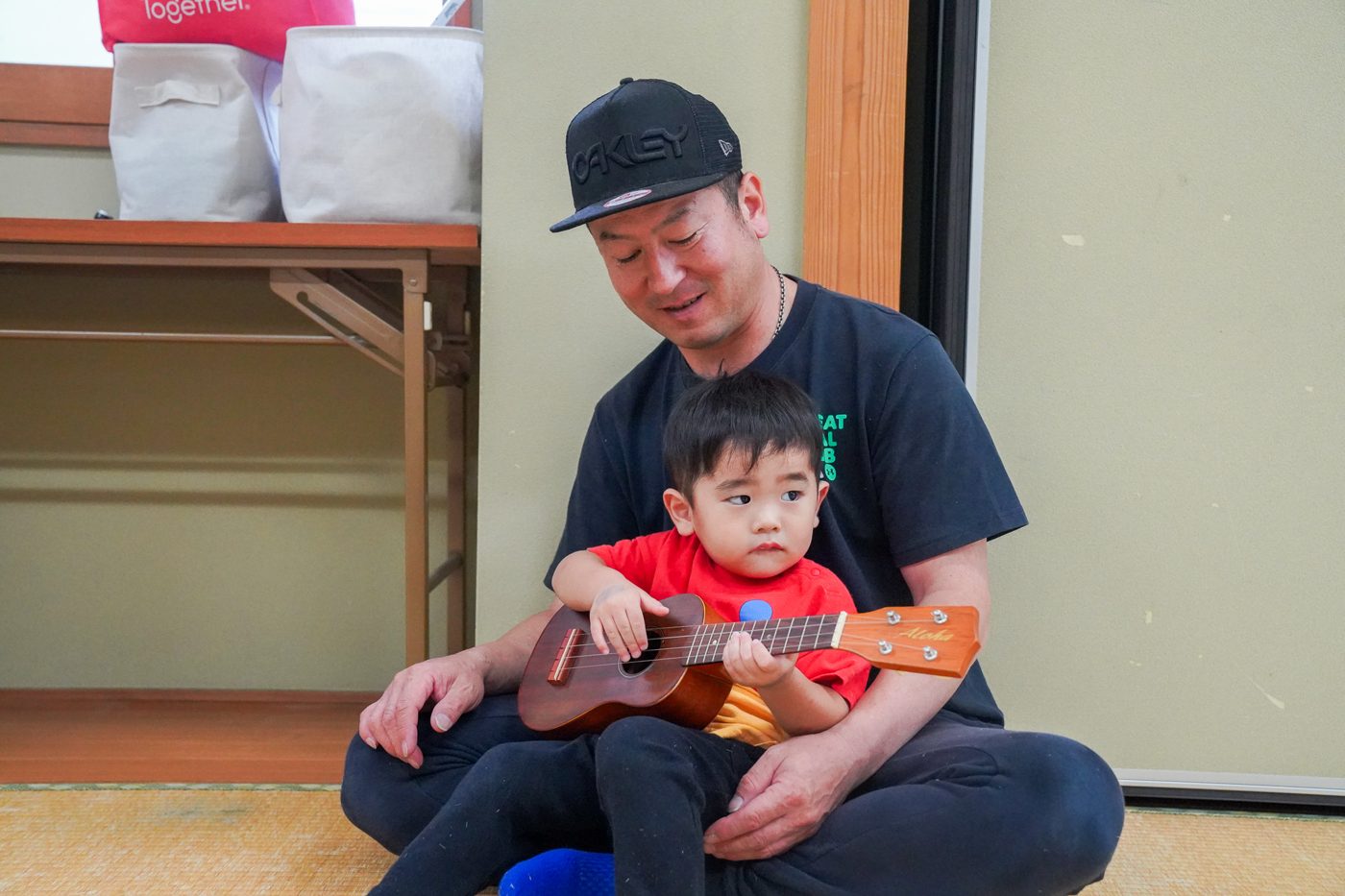 パパのおひざでウクレレにさわる男の子