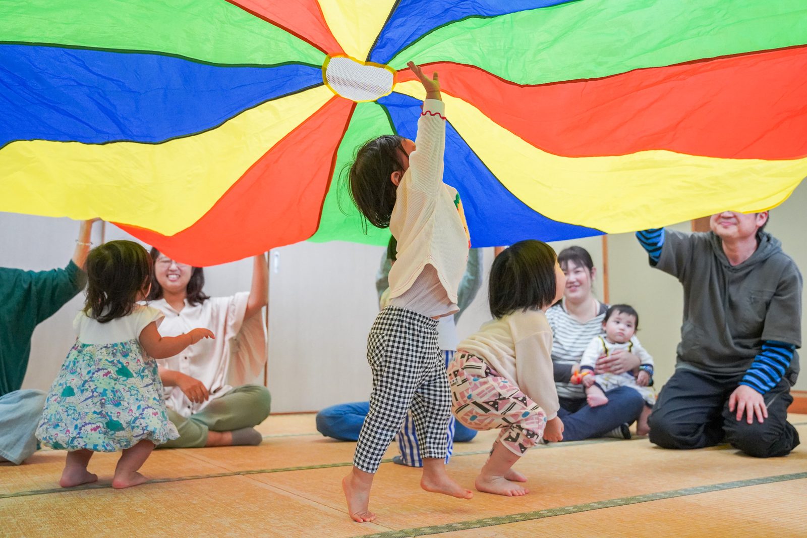 パラバルーンを持ち上げて、親子みんなで遊ぶ様子