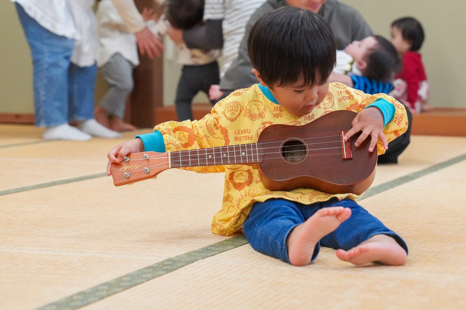 床に座ってウクレレを弾く男の子