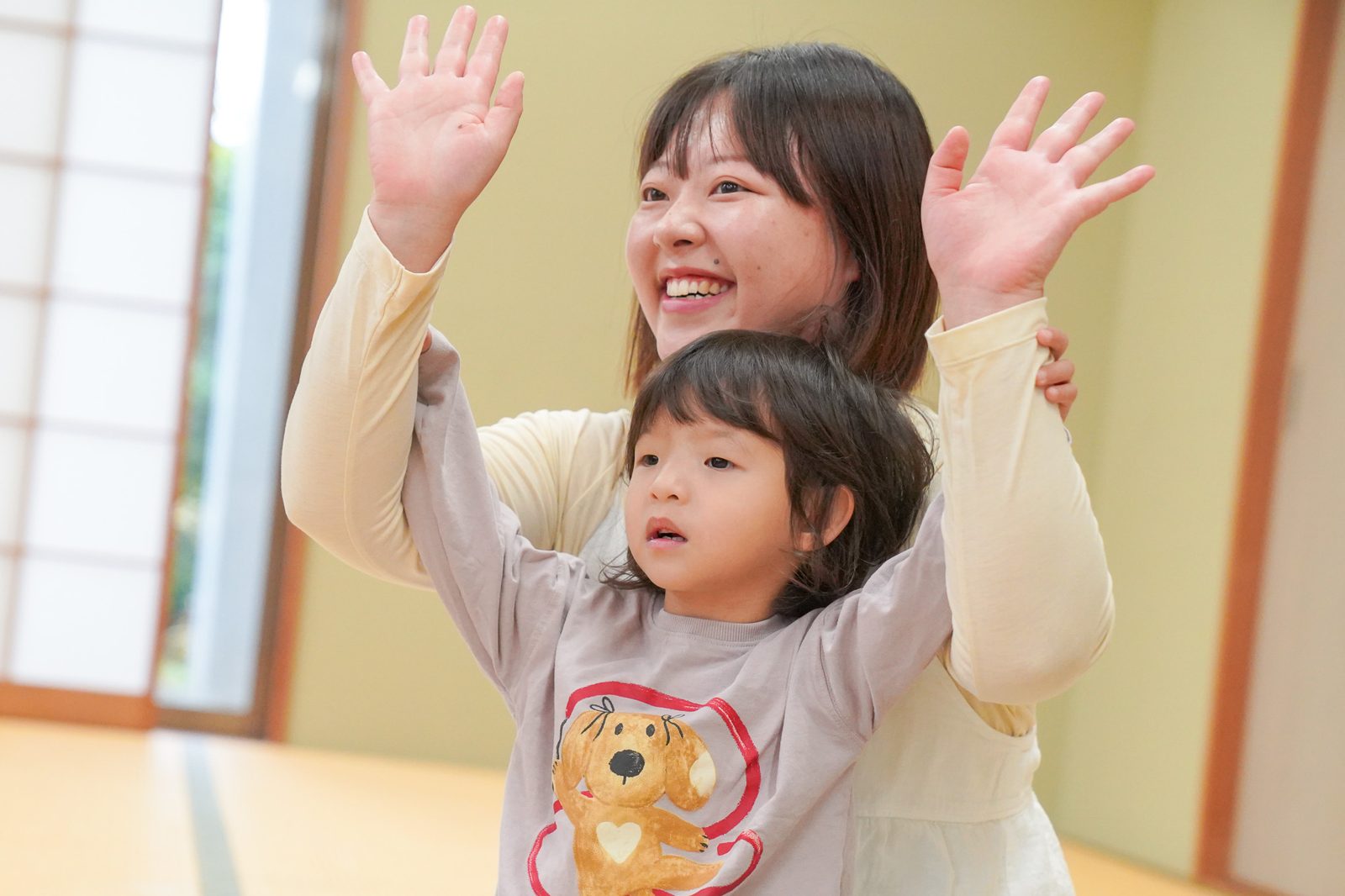 ママと娘さんが一緒に両手を上げて笑う様子