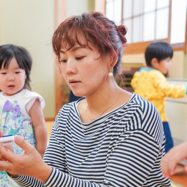 子どもたちに楽器を手渡すTOMOMI